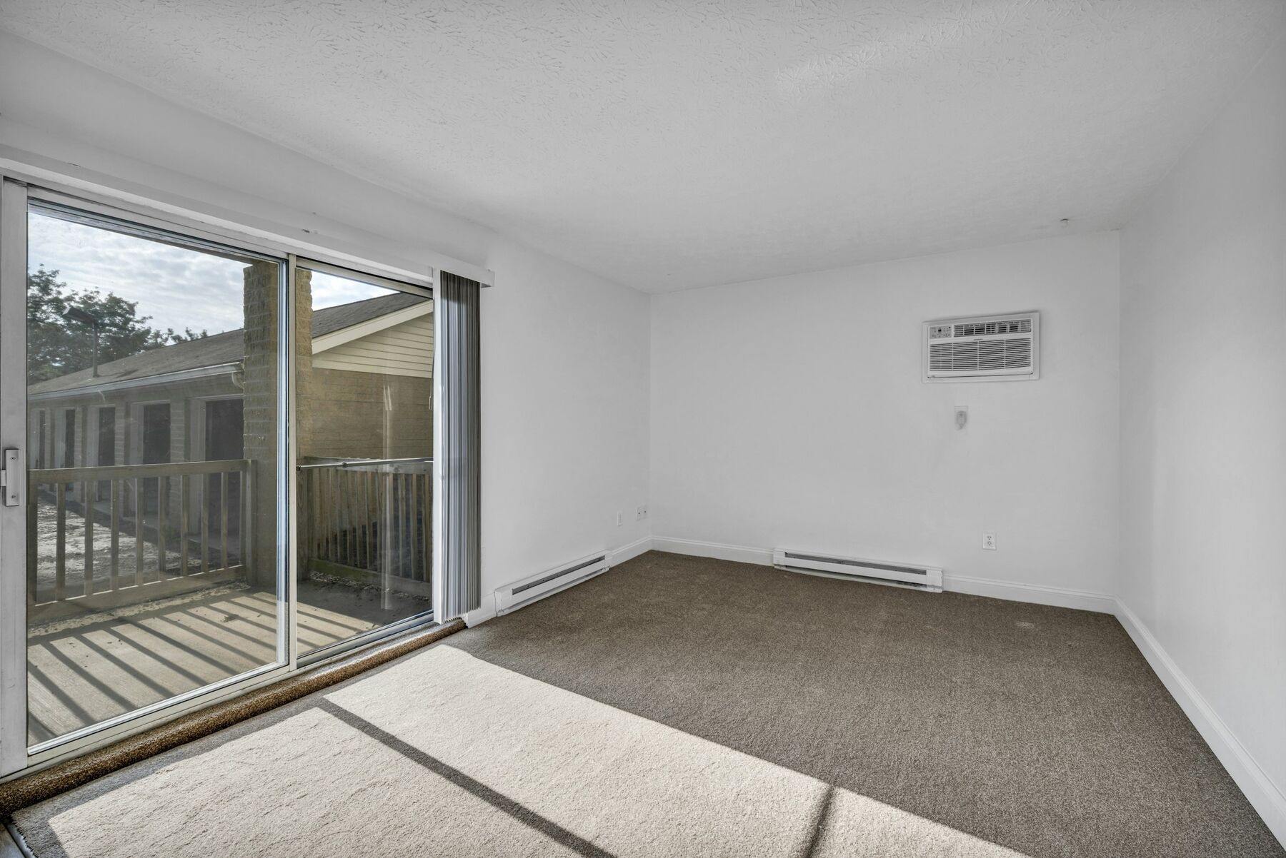 Empty carpeted living room with sliding doors, cleared out after a move